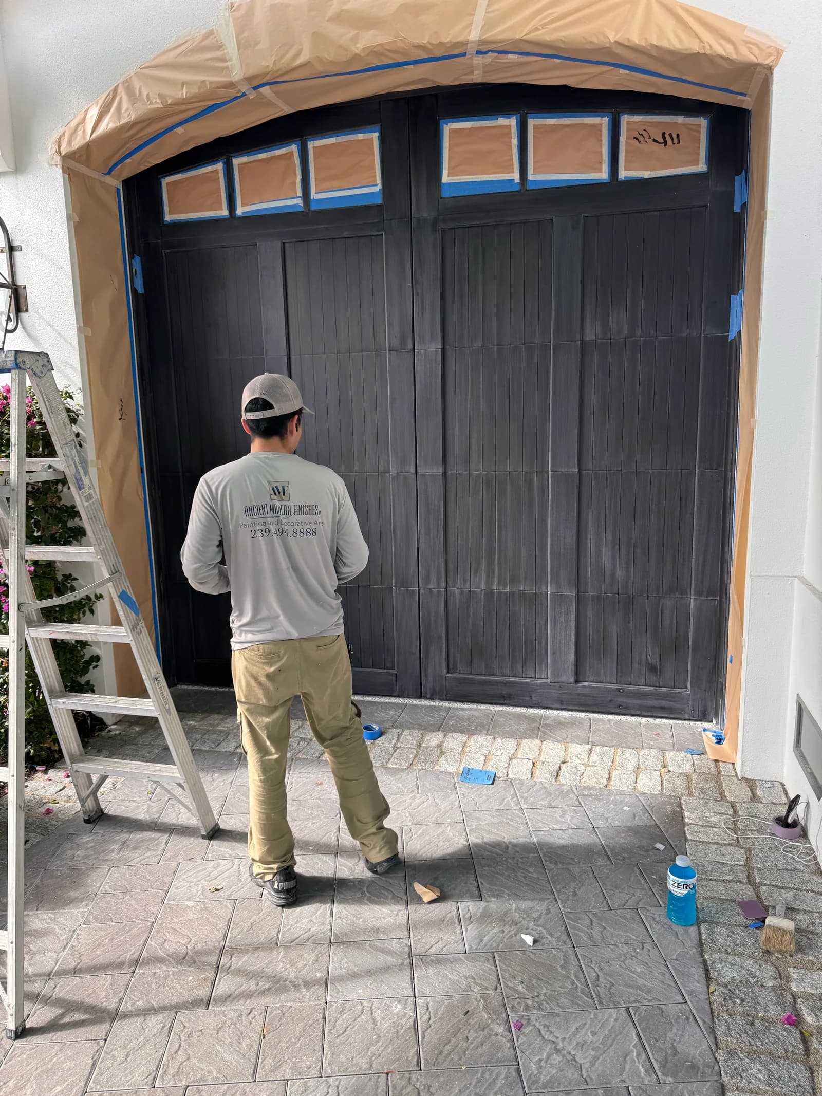 Crew member at an arched garage door under full masking