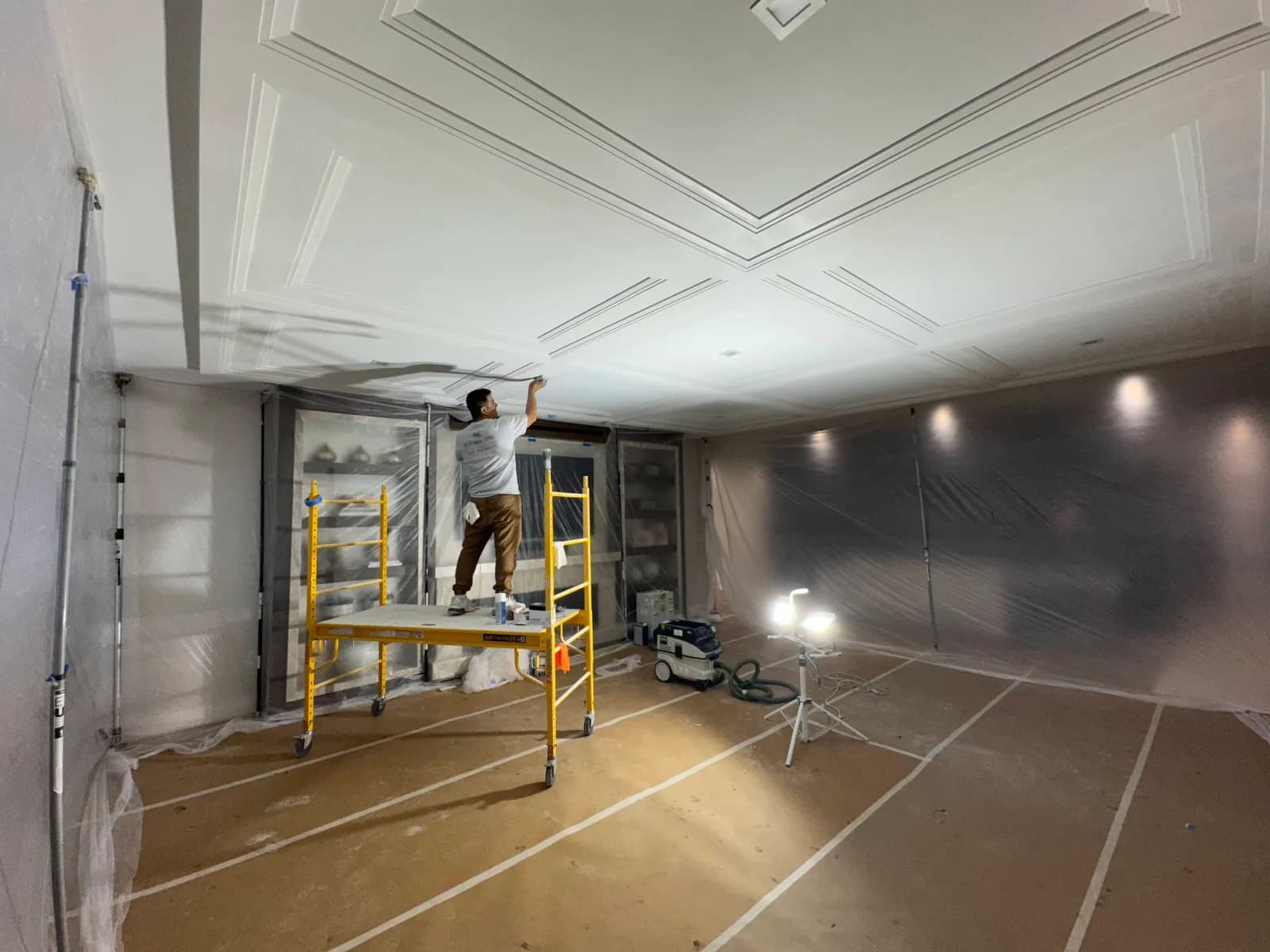 Painter on a rolling scaffold working a ceiling