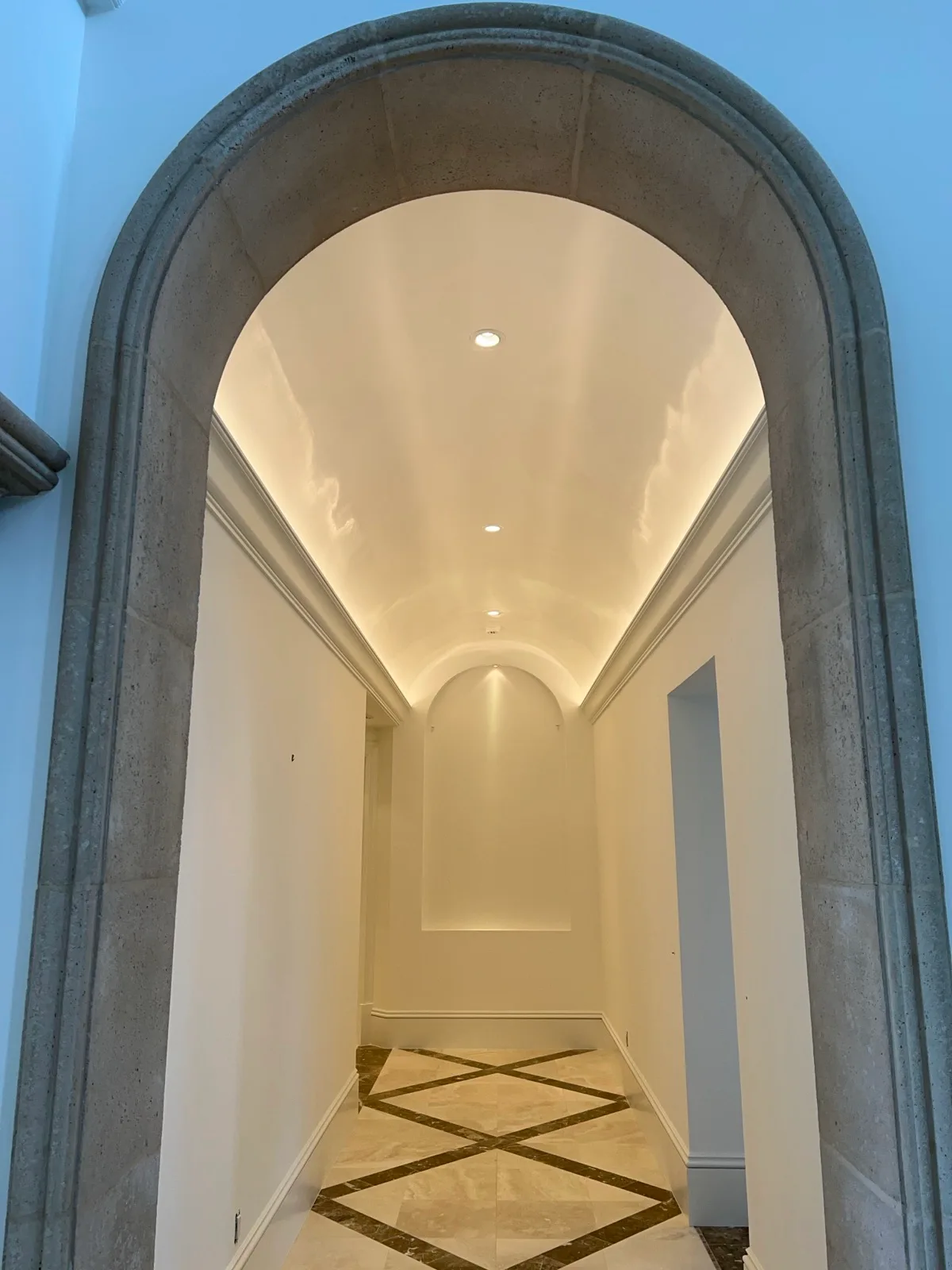 Plaster arch opening onto a barrel-vaulted hallway