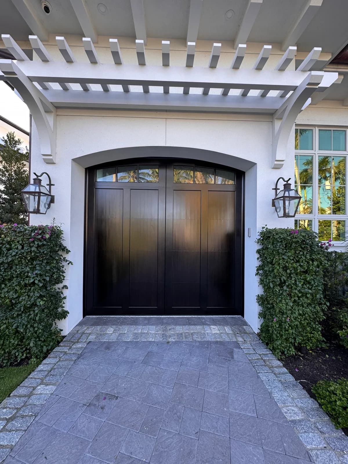 Arched garage door refinished under a painted pergola
