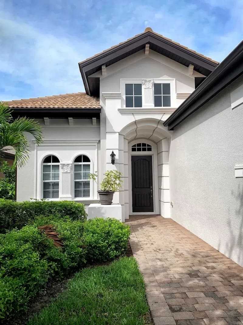 White stucco home with a repainted arched entry and tile roof